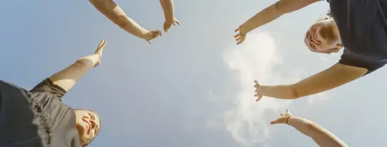 People with their arms in the air, enjoying th outdoors and blue sky