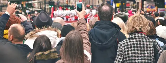 a street full of people watching a parade and filming it with their phones