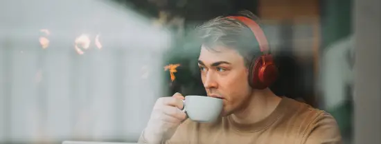 Een student luistert naar muziek en drinkt koffie.