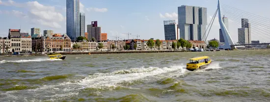 De skyline van Rotterdam met een varende watertaxi op de voorgrond.