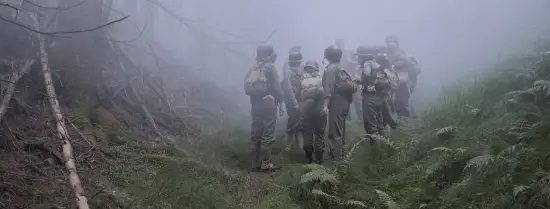 Re-enactmentgroep in actie in een mistig bos.