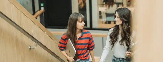 Twee vrouwelijke studenten lopen op de trap in een campusgebouw