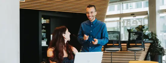 Twee medewerkers lachen naar elkaar op hun werkplek
