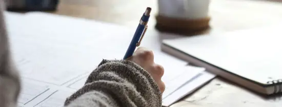 Person writing on paper with pen