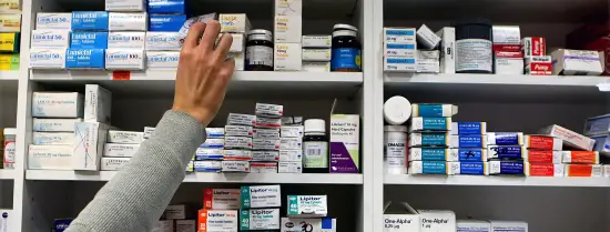 Een medewerker van een apotheek pakt medicijnen uit een voorraad.