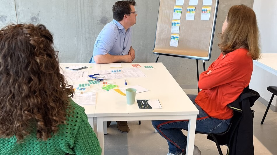 Drie onderzoekers zitten aan tafel terwijl ze aan het brainstormen zijn.