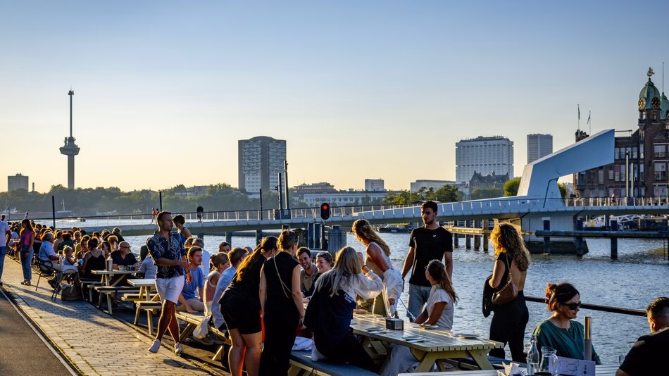 Summer evening in the Kop van Zuid, people sitting alongside the Maas.