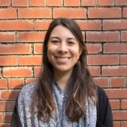 Portrait photo of Ellen Frank Delgado in front of a brick wall
