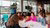 Groep jonge mensen met elkaar in gesprek rondom een tafel met papieren
